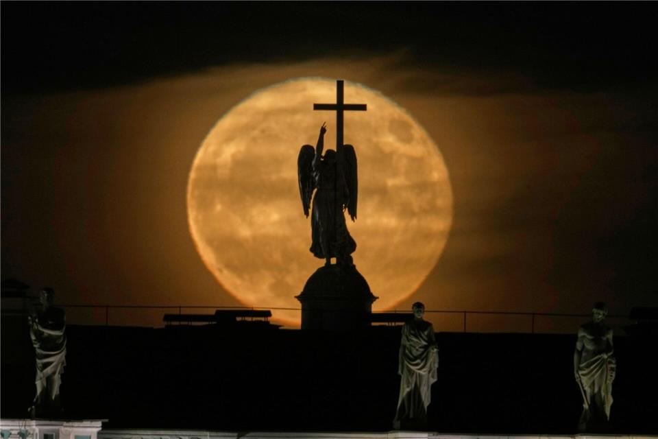 Der Mond geht hinter einer Engelsstatue auf der Alexandersäule auf dem Palastplatz über St. Petersburg auf.Dmitri Lovetsky/AP/dpa