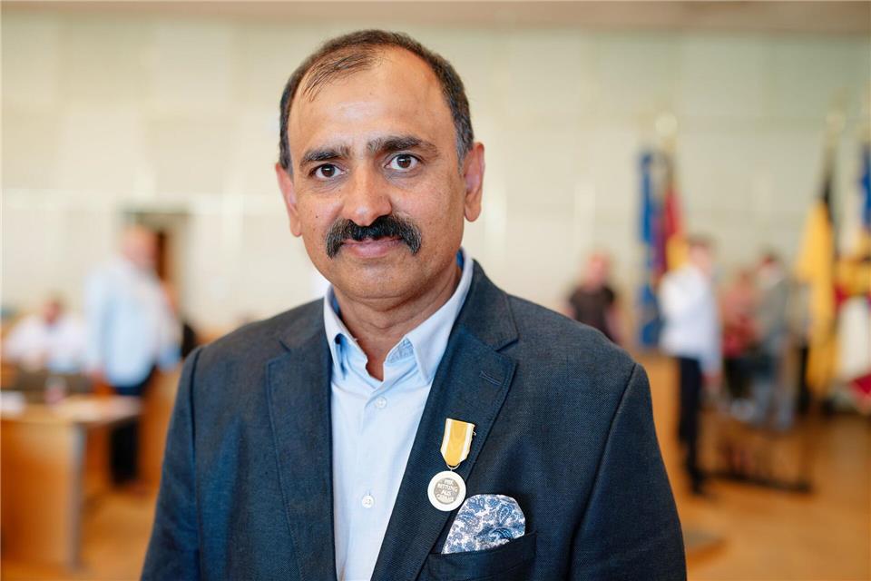 Der Taxifahrer Muhammad Afzal steht mit der Rettungsmedaille des Landes Baden-Württemberg im Ratssaal.Uwe Anspach/dpa