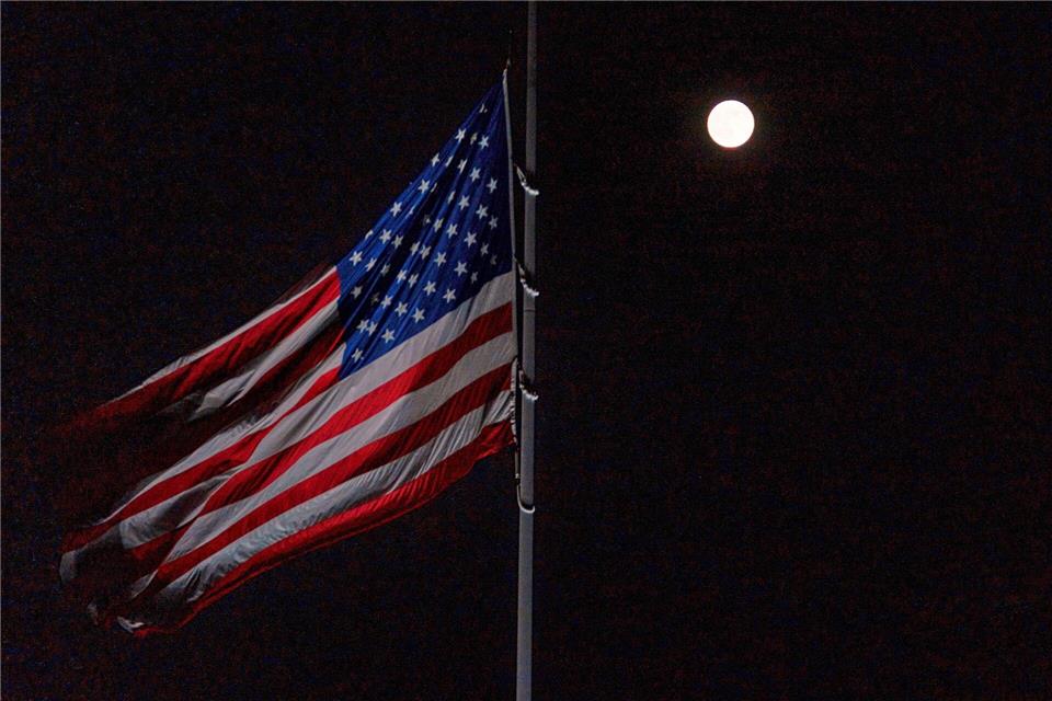 Der Vollmond geht hinter der auf Halbmast stehenden amerikanischen Flagge auf dem Südrasen des Weißen Hauses auf.Allison Robbert/AP/dpa