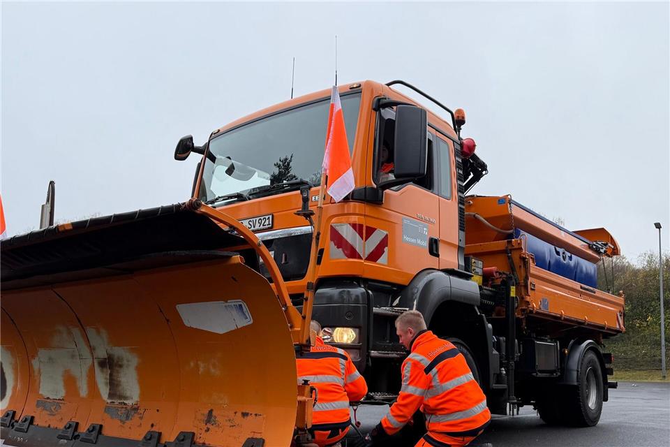 Der Winter kann kommen: In wenigen Minuten bringen Mitarbeiter des Winterdienstes einen Schneepflug an einem Lkw an.Michael Bauer/dpa
