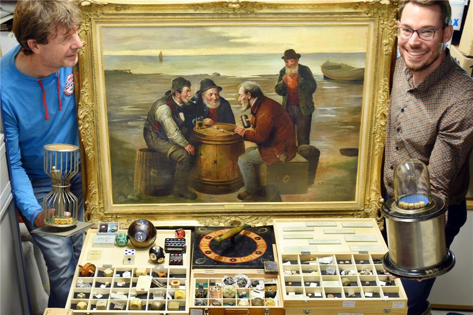Barockschloss Delitzsch zeigt Weihnachtsschau zum Würfeln Der Würfelspielesammler Jakob Gloger (r) steht mit seinem Vater Andre Gloger in seiner Würfelspielesammlung, zu der neben vielen Tausenden Würfel auch ein großes Gemälde gehört, das Fischer beim Würfeln auf einem Heringsfass um 1910 zeigt. Waltraud Grubitzsch/dpa