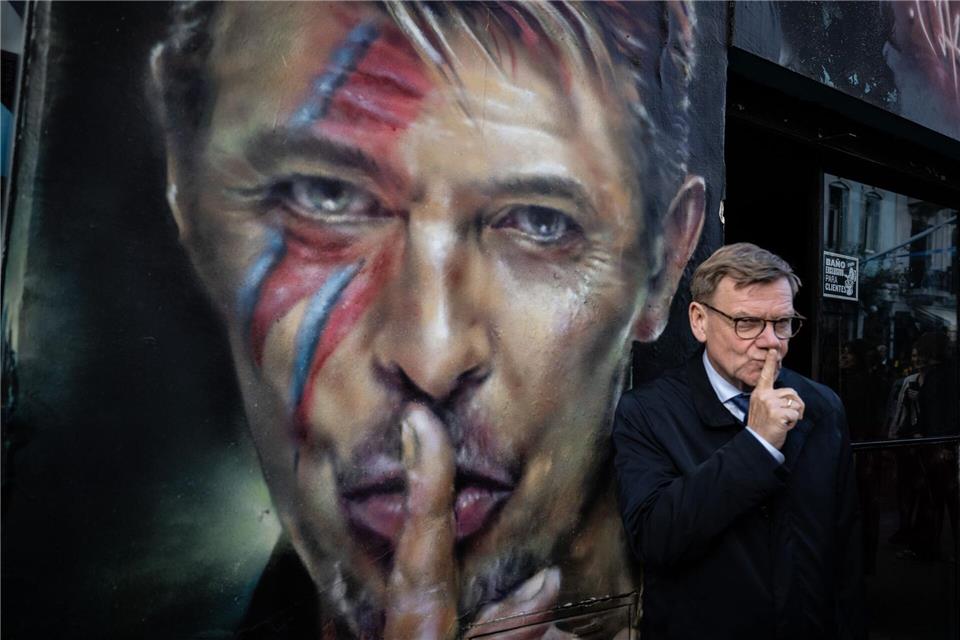 Der deutsche Außenminister Johann Wadephul (CDU) steht bei einem Rundgang durch das Stadtzentrum von Buenos Aires neben einem Graffiti von David Bowie.Boris Roessler/dpa