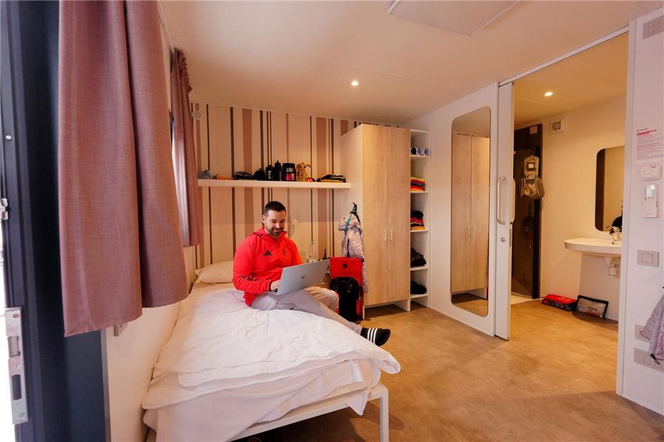 Der deutsche Skeleton-Trainer Christian Baude macht es sich im olympischen Dorf in Cortina gemütlich.Michael Kappeler/dpa