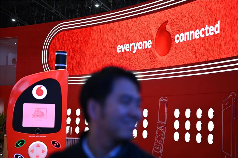 Der hat gut lachen: Ein Besucher der Mobilfunk-Messe MWC in Barcelona geht im März am Vodafone-Messestand vorbei, an dem ein überdimensionales Retro-Handy als Attrappe aufgebaut ist. Wolf von Dewitz/dpa