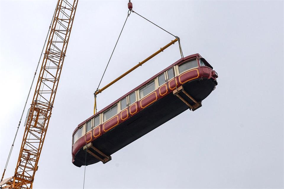 Der historische Schwebebahnwagen wird über mehrere über ein Gebäude in seine neue Position gehoben. Matthias Rosenkranz/dpa
