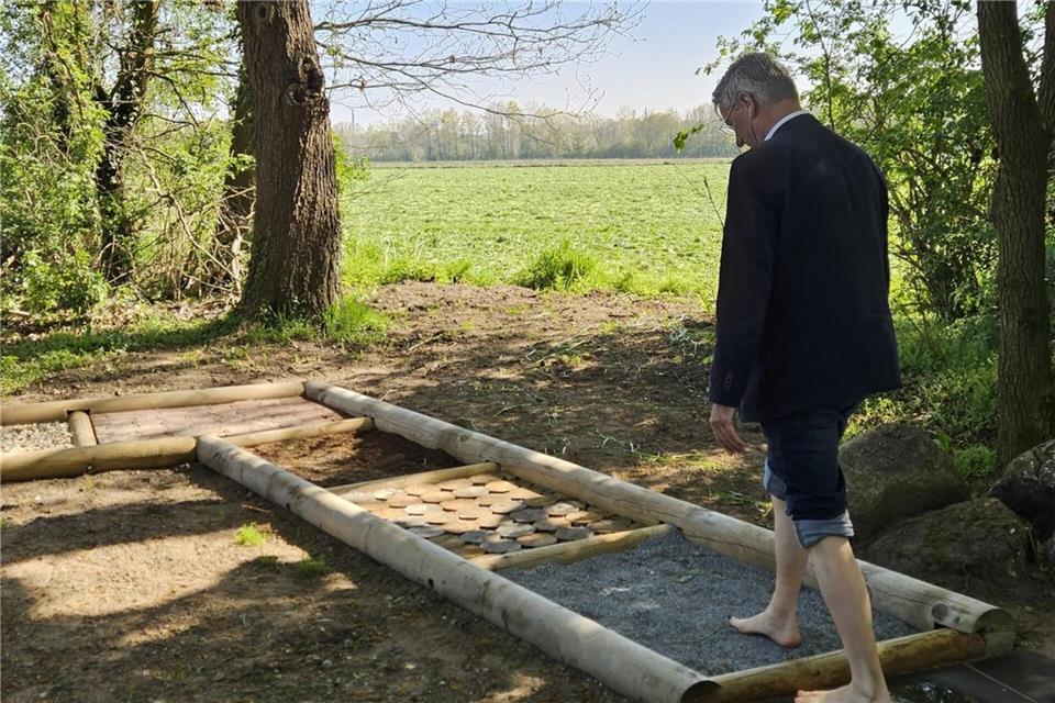 Der neue Barfußpfad am artesischen Brunnen wird von Bürgermeister Markus Hund ausprobiert.