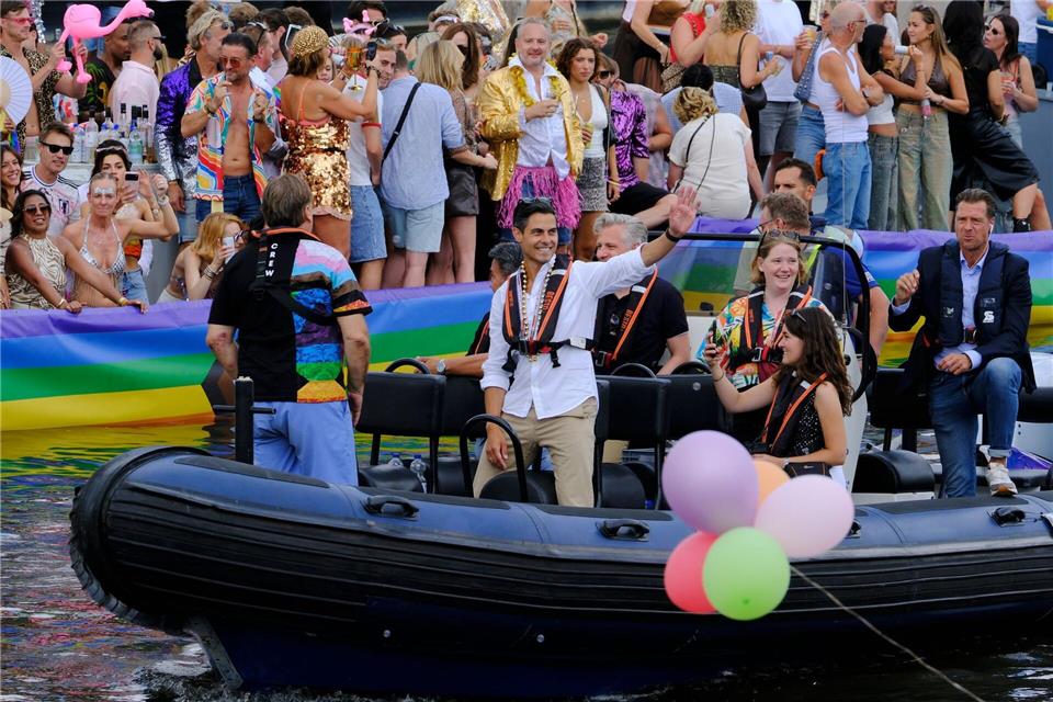 Der niederländische Ministerpräsident Rob Jetten steht auf einem Boot und winkt während der Canal Parade in Amsterdam.Patrick Post/AP/dpa
