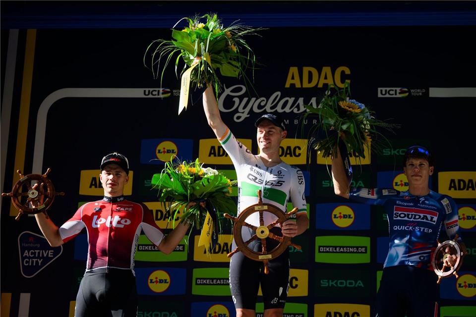 Der zweitplatzierte Belgier Arnaud De Lie (l-r), der Sieger aus Irland Rory Townsend und der drittplatzierte Franzose Paul Magnier bei der Siegerehrung der Cyclassics.Gregor Fischer/dpa