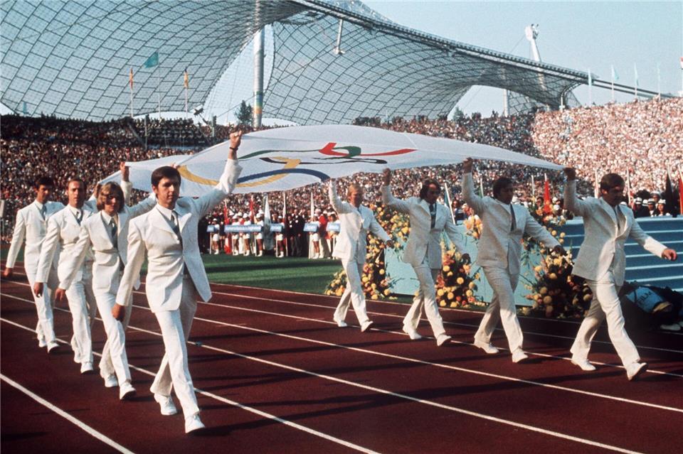 Die lange Geschichte der Sportstadt München Deutsche Sportler tragen 1972 bei der Eröffnungsfeier die Olympia-Fahne in das Münchner Olympiastadion (Archivbild).-/Olympische_Spiele/dpa