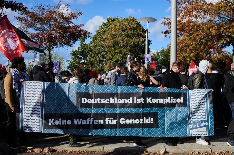 „Deutschland ist Komplize! Keine Waffen für Genozid“ steht auf einem Transparent, das Teilnehmer einer propalästinensischen Demonstration zeigen. Annette Riedl/dpa