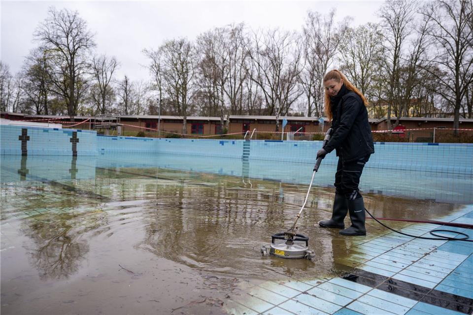 Diana Reimann, Badleiterin vom Sommerbad Humboldthain der Berliner Bäder-Betriebe, reinigt die Fliesen im Schwimmbecken. (Archivbild) Christophe Gateau/dpa