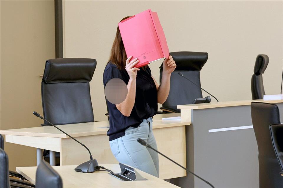 Die Angeklagte betritt den Gerichtssaal mit rotem Aktendeckel vor dem Gesicht.A7120 Bernd Wüstneck/dpa
