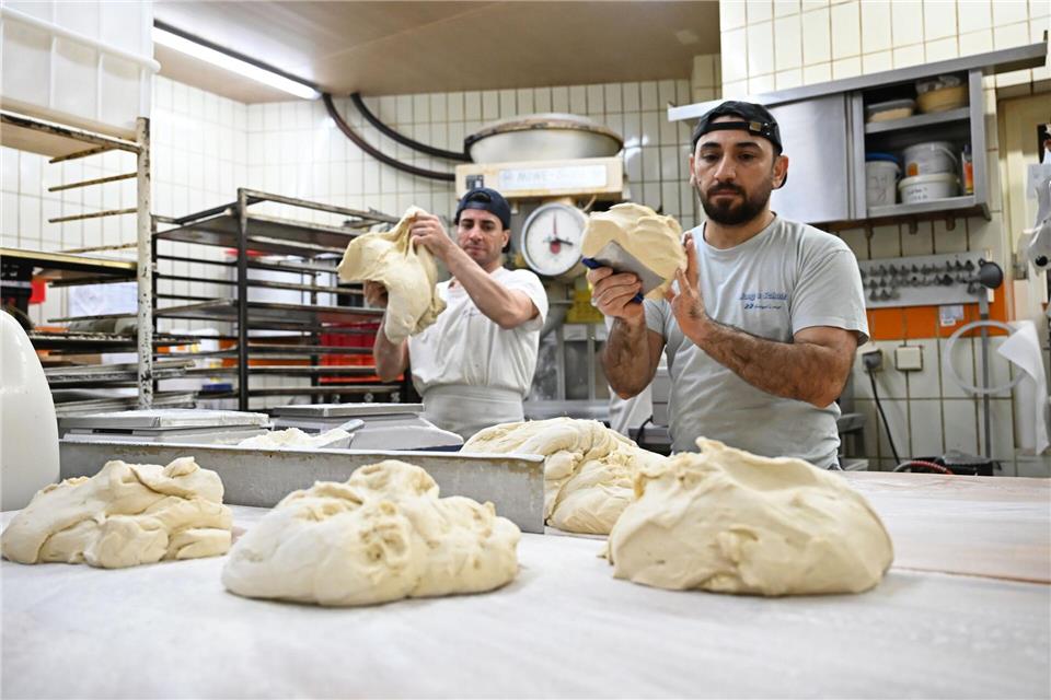 Die Bäcker Subhan Ullah (l) und Sulaiman Shapal kneten Teig in einer Backstube. Beide sind als Migranten aus Afghanistan und Syrien nach Deutschland gekommen.Michael Brandt/dpa