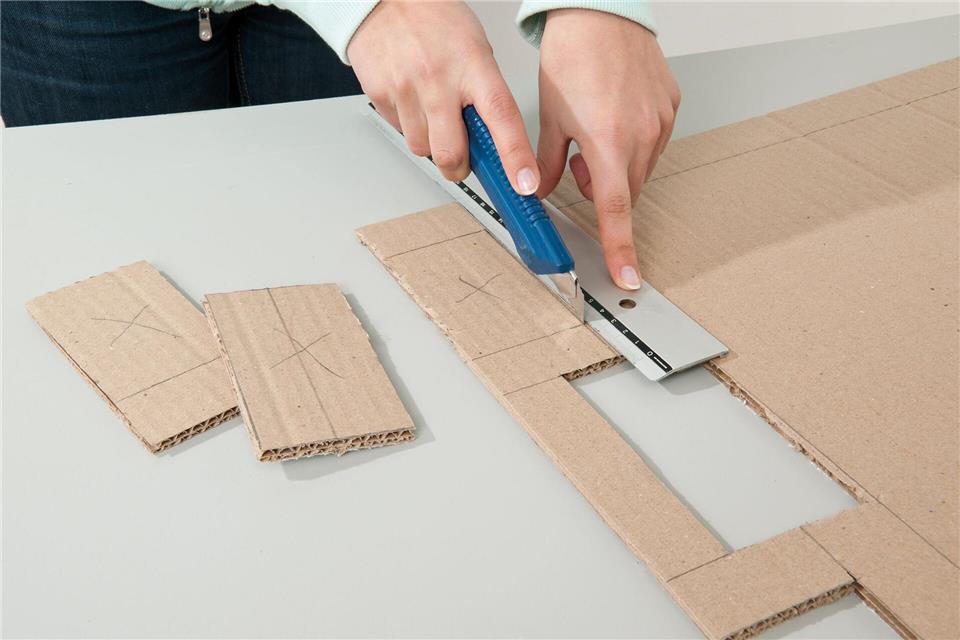 Die Basis fürs Wohnzimmer-Stadion: Aus einem Kartonstück entstehen Spielfeld, Banden und Tore – am besten mit Cuttermesser und Metalllineal.-/Tesa/DIY Academy/dpa-tmn