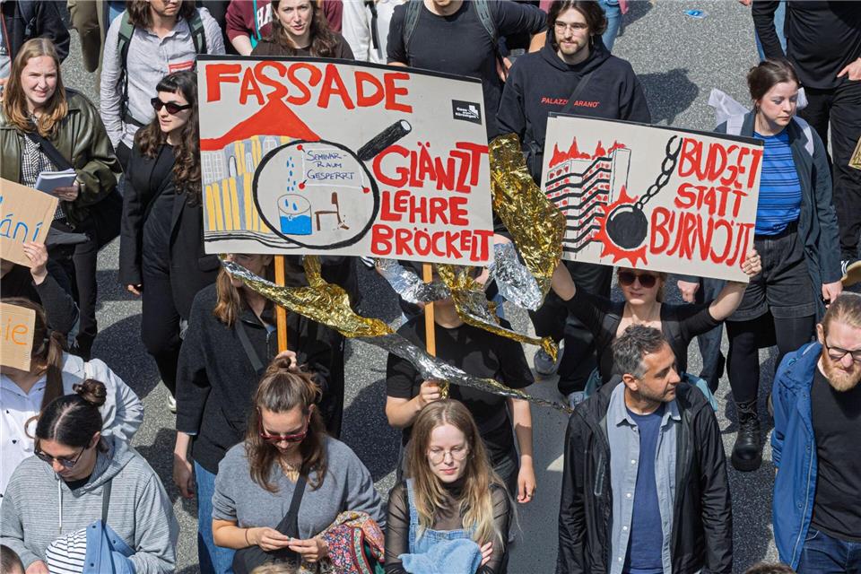 Die Demonstranten tragen Schilder etwa mit der Aufschrift „Fassade glänzt, Lehre bröckelt“ oder „Budget statt Burnout“.Markus Scholz/dpa