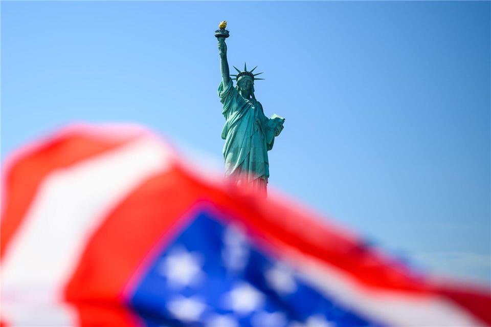 Die Fahne der USA weht vor der Freiheitsstatue.Tom Weller/dpa