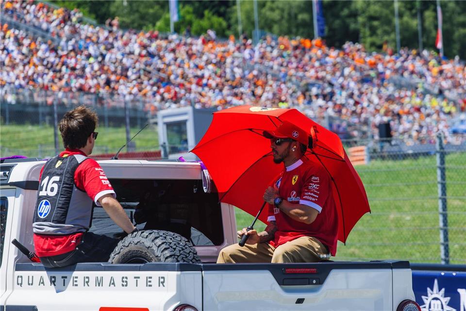 Die Ferrari-Fahrer Charles Leclerc (links) und Lewis Hamilton schützen sich im Vorjahr mit einem Schirm und einer Kühlweste vor der Hitze. Auch am Wochenende wird es in Spielberg heiß. (Archivbild)Philipp von Ditfurth/dpa