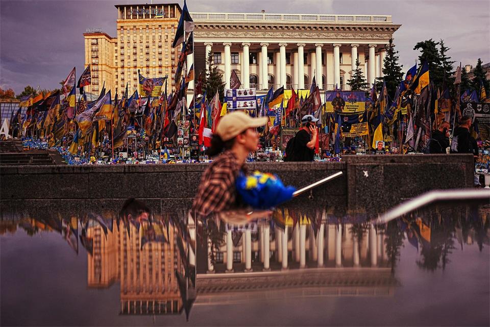 Die Nationale Musikakademie (r) spiegelt sich in einem U-Bahn-Eingang am Unabhängigkeitsplatz in Kiew wider, wo ukrainische Flaggen und Fotos zum Gedenken an die im Krieg mit Russland getöteten Zivilisten und Soldaten aufgestellt sind.Francisco Seco/AP/dpa