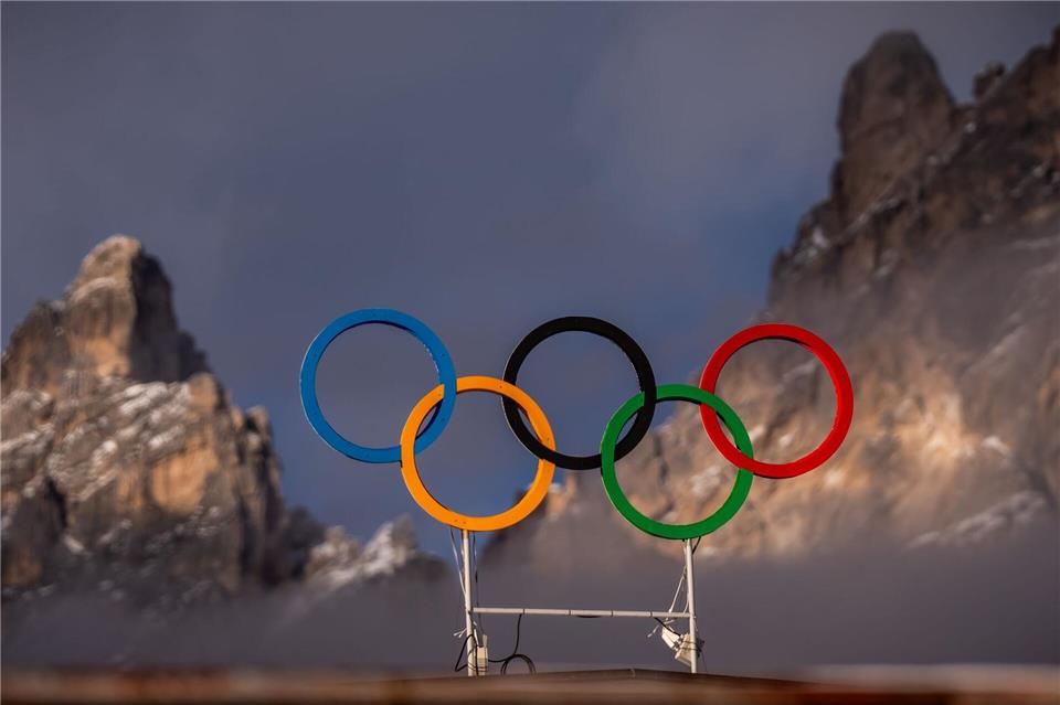 Die Olympischen Ringe auf dem Dach der Curling Halle sind vor den Bergen in Cortina zu sehen. Die Olympischen Winterspiele 2026 finden in Mailand und Cortina d’Ampezzo statt.Michael Kappeler/dpa