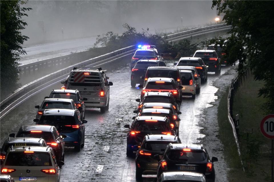 Die Polizei leitet den Verkehr auf der Bundesstraße 4 bei Erlangen-Tennenlohe an umgestürzten Bäumen vorbei.Bernd März/Fotoreportextremwetter.tv/dpa