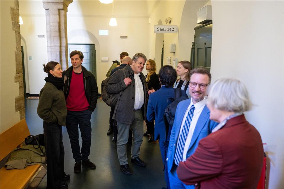 Die Prozessbeteiligten stehen im Landgericht II vor einem Gerichtssaal. Christophe Gateau/dpa