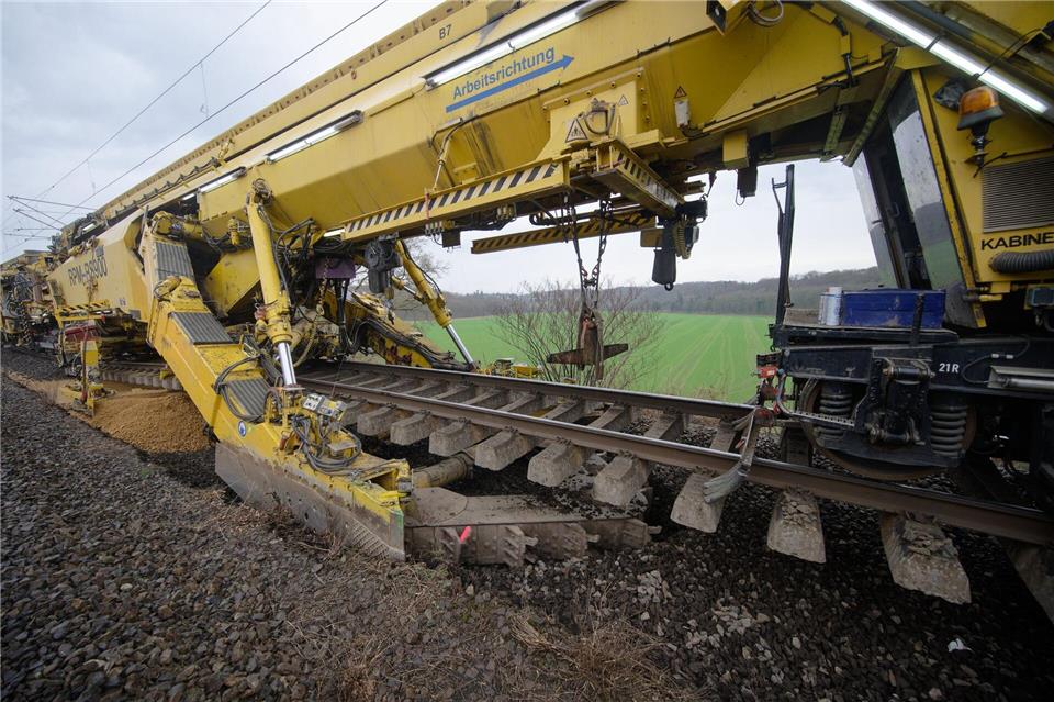 Die Schienen werden in die Höhe gehoben, dann gräbt die Maschine den alten Schotter weg.Henning Kaiser/dpa