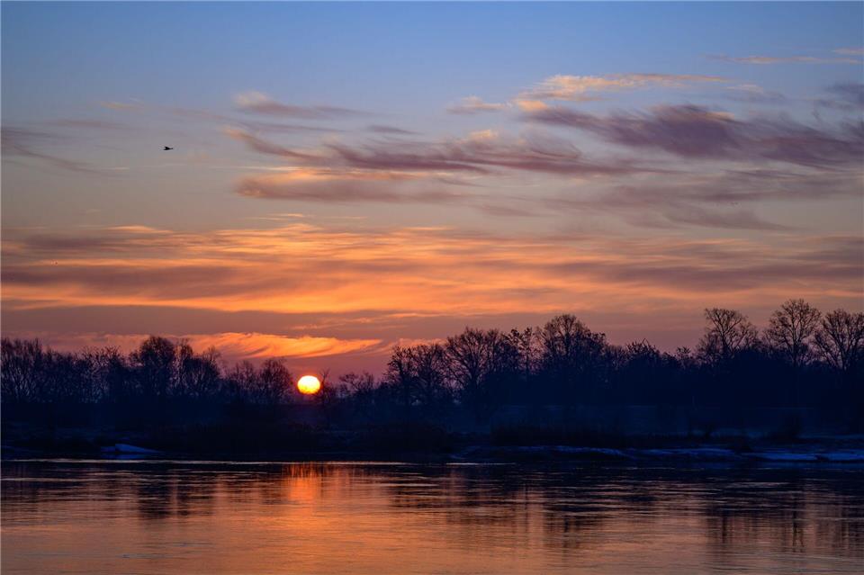 Die Sonne geht auf. Dabei sind nur wenige Wolken am Himmel. (Archivfoto)Patrick Pleul/dpa