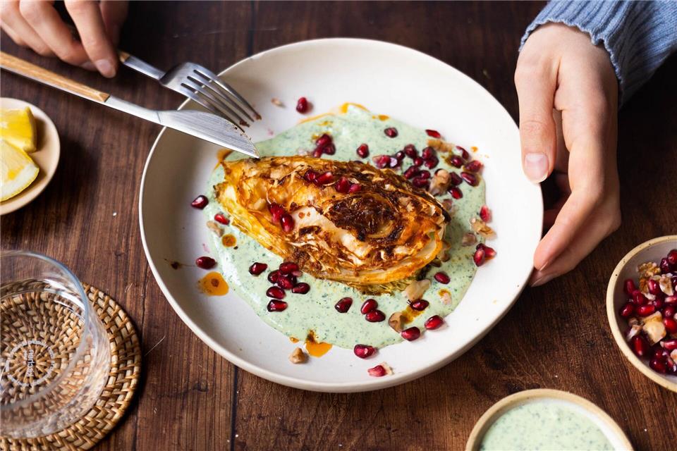 Die Spitzkohl-Viertel werden vor dem Backen kurz in der Pfanne angebraten. Nach 40 Minuten im Ofen werden sie auf Kräuterjoghurt gebettet und mit Granatapfelkernen und Walnüssen getoppt.Zucker&Jagdwurst/zuckerjagdwurst.com/dpa-tmn