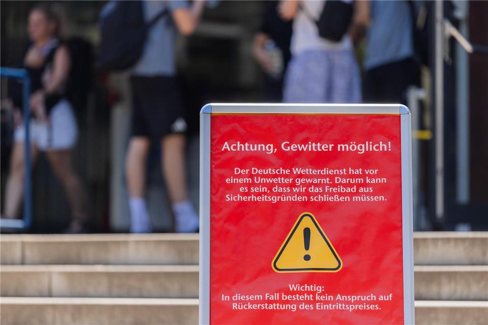 Die Stadt Köln weist am Eingang zum Stadionbad mit einem Aufsteller auf ein mögliches Gewitter hin. Hitze und Gewitter sind für NRW vorhergesagt. Rolf Vennenbernd/dpa