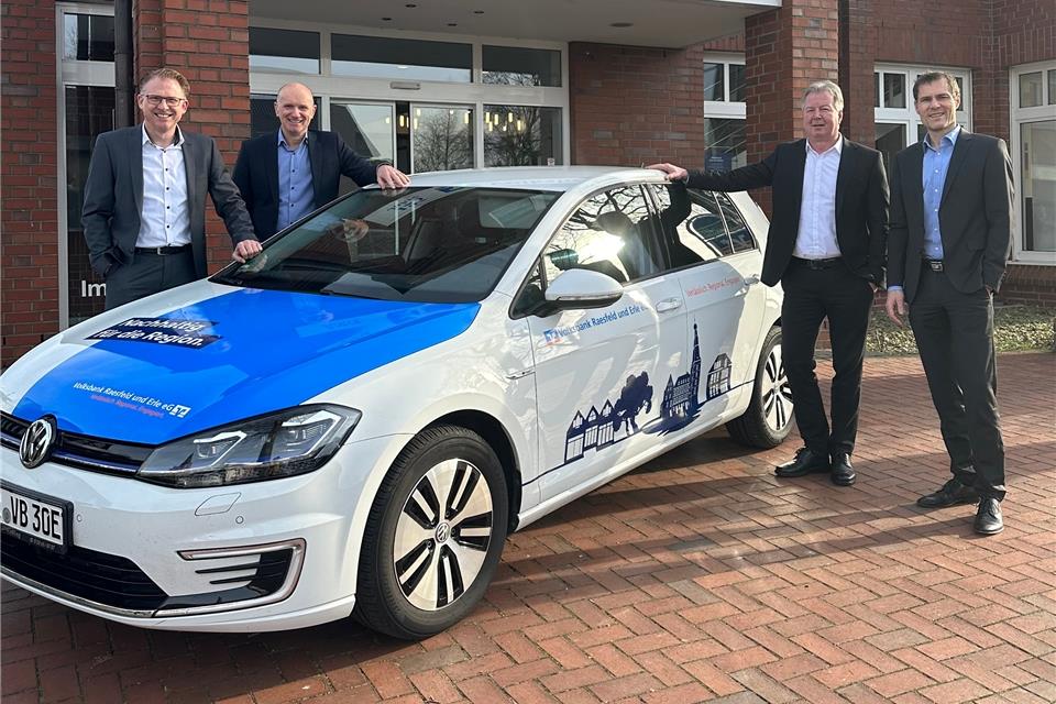 Die Vorstandsmitglieder Michael Weddeling, Ralf Steiger, Oliver Cichowski und Marcus Feldhaar präsentieren ein Elektroauto mit dem neuen Unternehmensslogan.