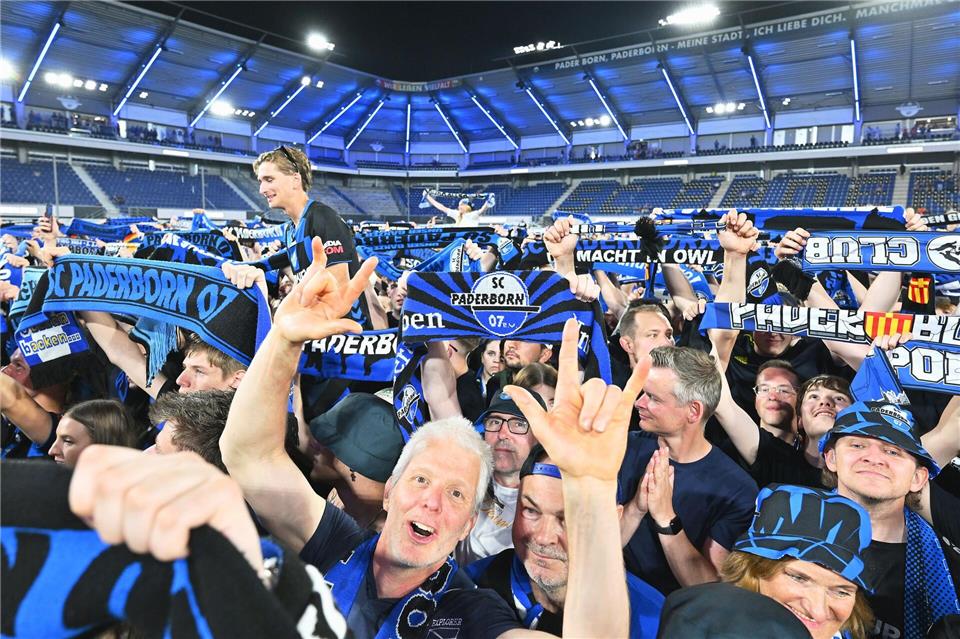 Die Zuschauer im Stadion feiern und halten Schals in die Höhe.Swen Pförtner/dpa