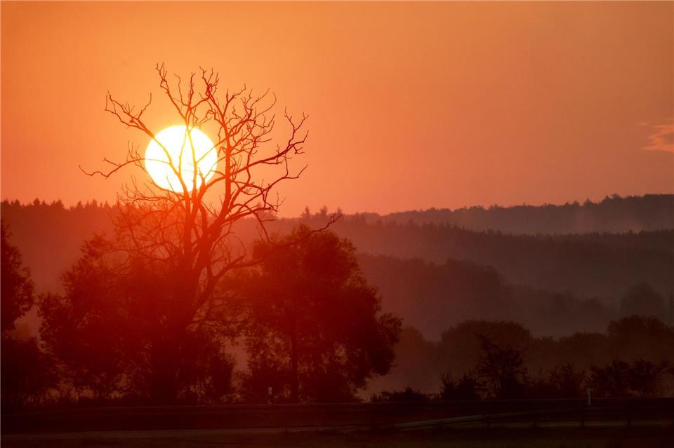 Die aufgehende Sonne färbt den Himmel am Morgen rot.Thomas Warnack/dpa