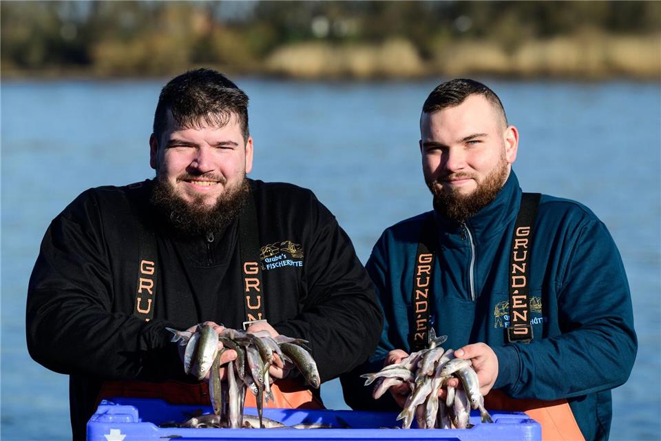 Die beiden Brüder und Fischer Per-Willem (l) und Jonas Grube halten frischen Stint in den Händen. Philipp Schulze/dpa