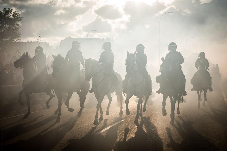 Die berittene Polizei reitet im Rauch während der Einsätze im Vorfeld des Spiels Atlético Madrid gegen FC Arsenal in der Champions League.Diego Radames/Europapress/dpa