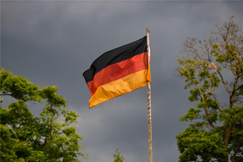 Die deutsche Flagge weht vor dunklen Wolken im Wind. (Symbolbild)Kira Hofmann/dpa-Zentralbild/dpa
