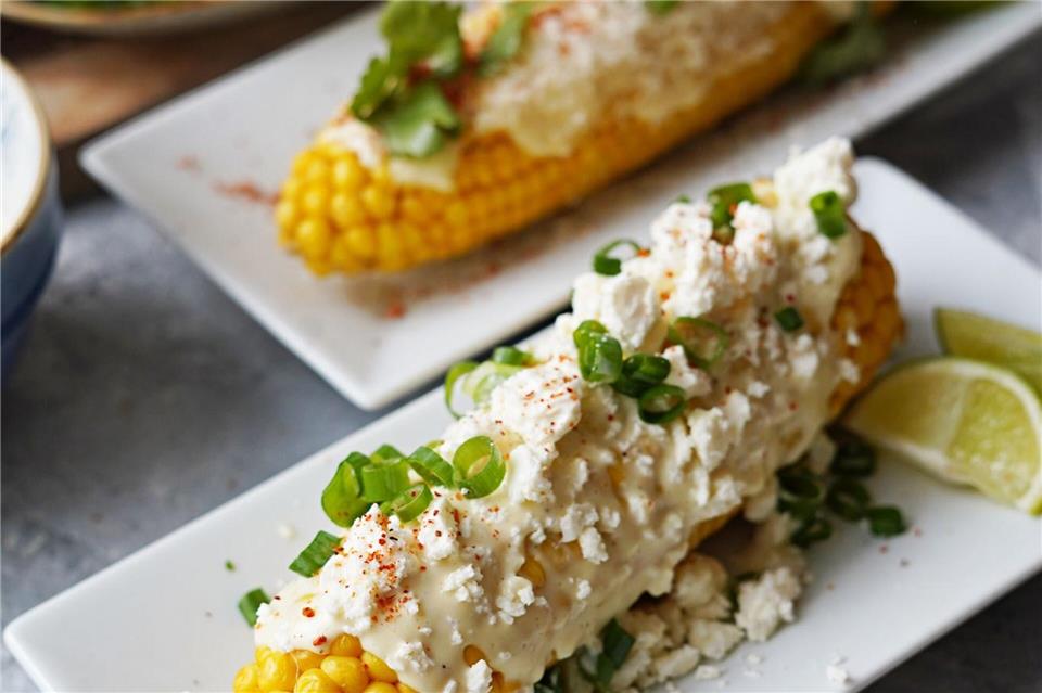 Die fertigen Maiskolben bekommen ein „Zudecke“ aus selbstgemachter Mayo und Dingen, die der Kühlschrank gerade so hergibt - etwa Parmesan, Feta, Frühlingszwiebel und Rucola.Mareike Pucka/biskuitwerkstatt.de/dpa-tmn