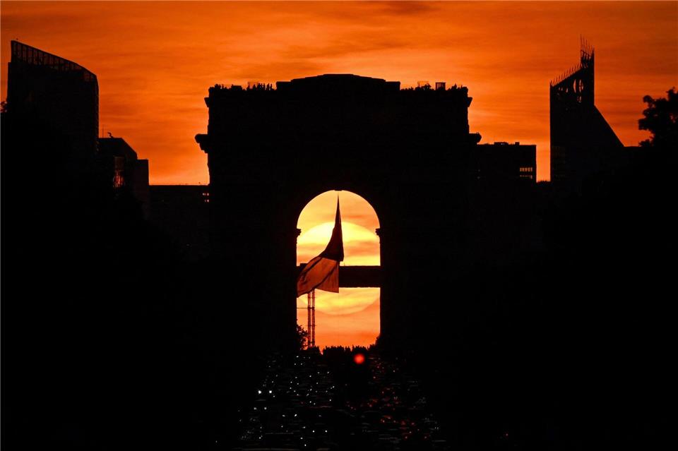 Die französische Nationalflagge weht unter dem Arc de Triomphe auf der Avenue des Champs Elysees während des sogenannten „Paris Henge“-Phänomens.Christophe Delattre/AFP/dpa