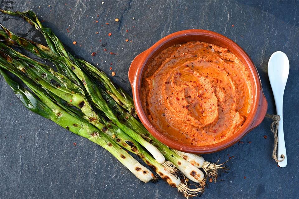 Die gegrillten Frühlingszwiebeln müssen nur noch in den katalanischen Paprika-Dip eingetunkt werden und in den Mund wandern - dann kann das Gaumenfeuerwerk starten.Julia Uehren/dpa-tmn