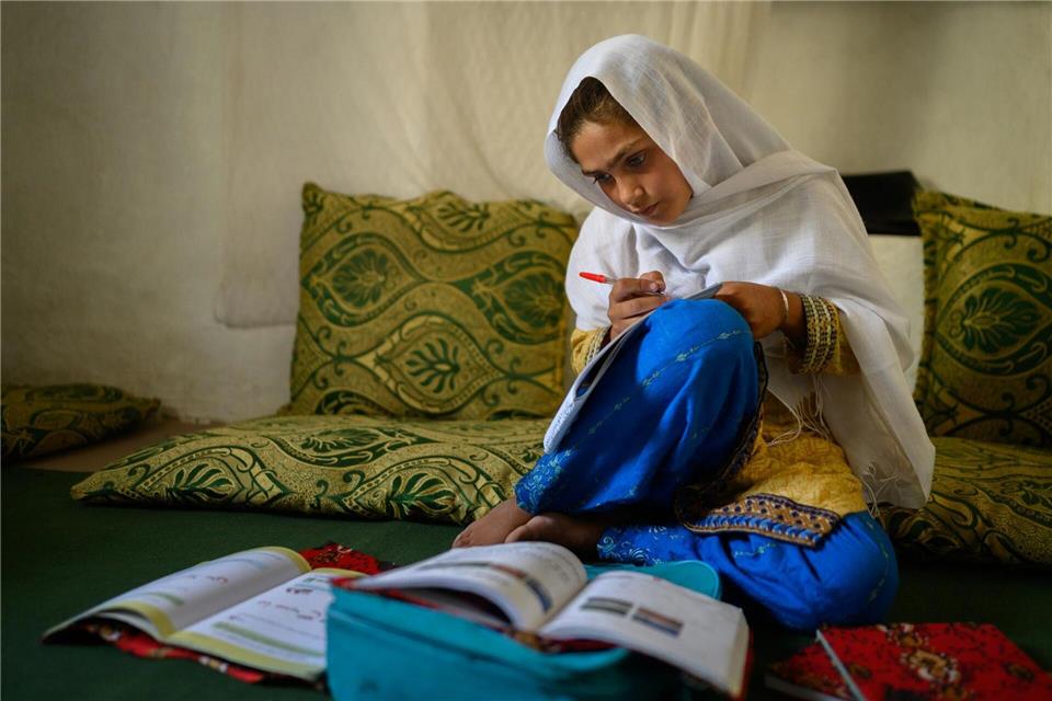 Die zehnjährige Hajira aus der afghanischen Provinz Nangarhar sitzt in einem Haus in einem abgelegenen Dorf östlich von Kabul über Schulbüchern und lernt. Elise Blanchard/Unicef/dpa