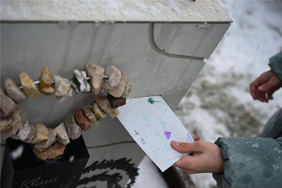 Die zehnjährige Ida wirft einen Brief an ihren Vater in den Briefschlitz am Grabstein.Katharina Kausche/dpa