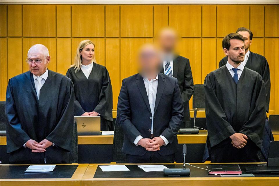 Die zwei angeklagten Brüder aus Oelde (vorne und hinten Mitte) stehen beim Einzug der Richter zwischen ihren vier Verteidigern. Lars Berg/dpa
