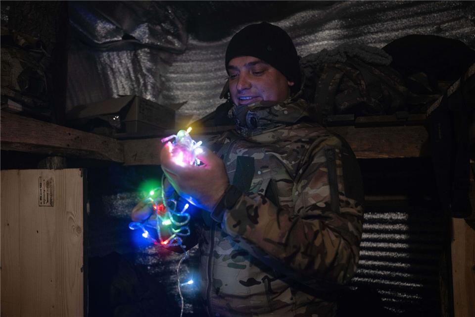 Dieses vom Pressedienst der 93. mechanisierten Brigade der Ukraine zur Verfügung gestellte Foto zeigt einen Soldaten an der Frontlinie in der Nähe von Kostjantyniwka in der Region Donezk, der eine Neujahrsgirlande hält.Iryna Rybakova/Ukrainian 93rd Mechanized brigade/AP/dpa
