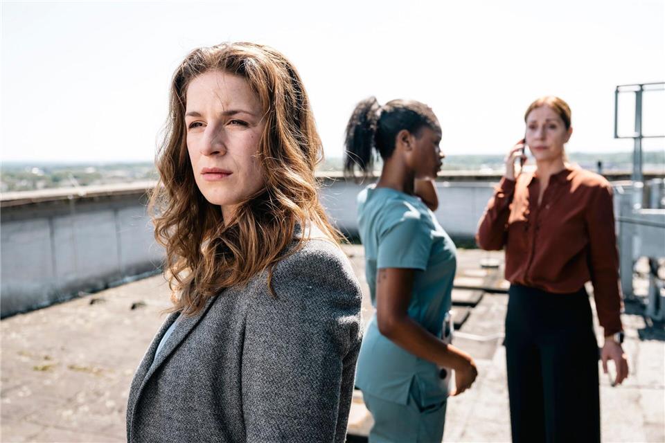 Dina Schwarz (Lou Strenger, links) blickt zu dem am Dach-Rand stehenden Nathan Freye. Im Hintergrund rufen Veronika Jelinek (Ulrike Tscharre, rechts) und Jenny de Luca (Melodie Simina, Mitte) Hilfe.Martin Rottenkolber/WDR Kommunikation/Redaktion Bild/dpa