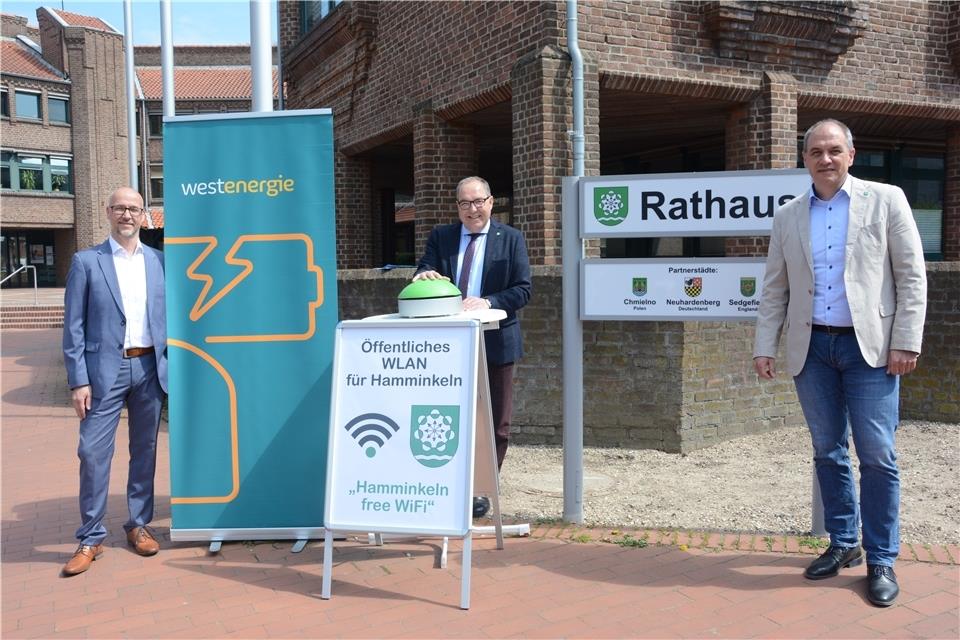 Dirk Krämer, Kommunalberater von Westenergie (von links), Bürgermeister Bernd Romanski und Vorstandsbereichsleiter Bernhard Payer nehmen das öffentliche WLAN-Netz in Betrieb. Den grünen Buzzer drückt Romanski aber nur symbolisch.