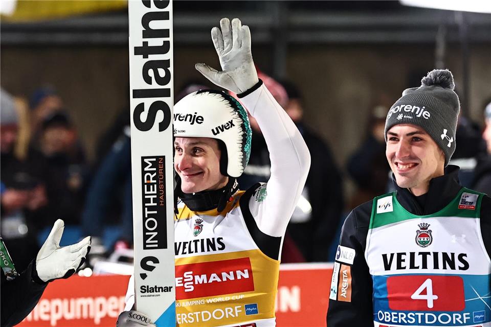 Domen Prevc (l) freut sich über den Sieg, sein Landsmann Timi Zajc wird später disqualifiziert.Daniel Karmann/dpa