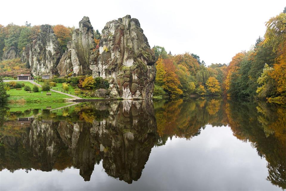 Doppeltes Herbstpanorama: Die Externsteine und herbstlich verfärbtes Laub spiegeln sich im Wasser vor dem Naturmonument. Marcel Kusch/dpa/dpa-tmn