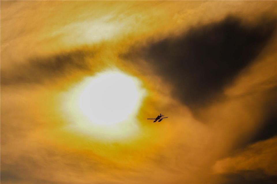 Durch dunkle Rauchschwaden: Ein schwedisches Löschflugzeug fliegt über dem Brandgebiet im Hohen Venn.Christoph Reichwein/dpa