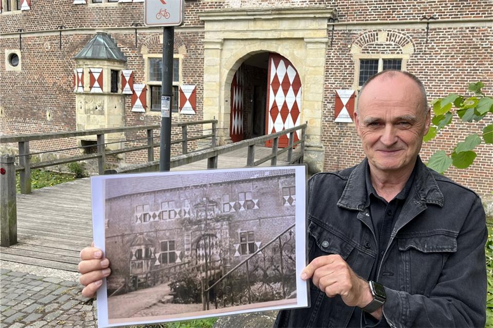Eberhard Berg zeigt ein historisches Foto der Vorburg. Im Hintergrund das restaurierte Tor.