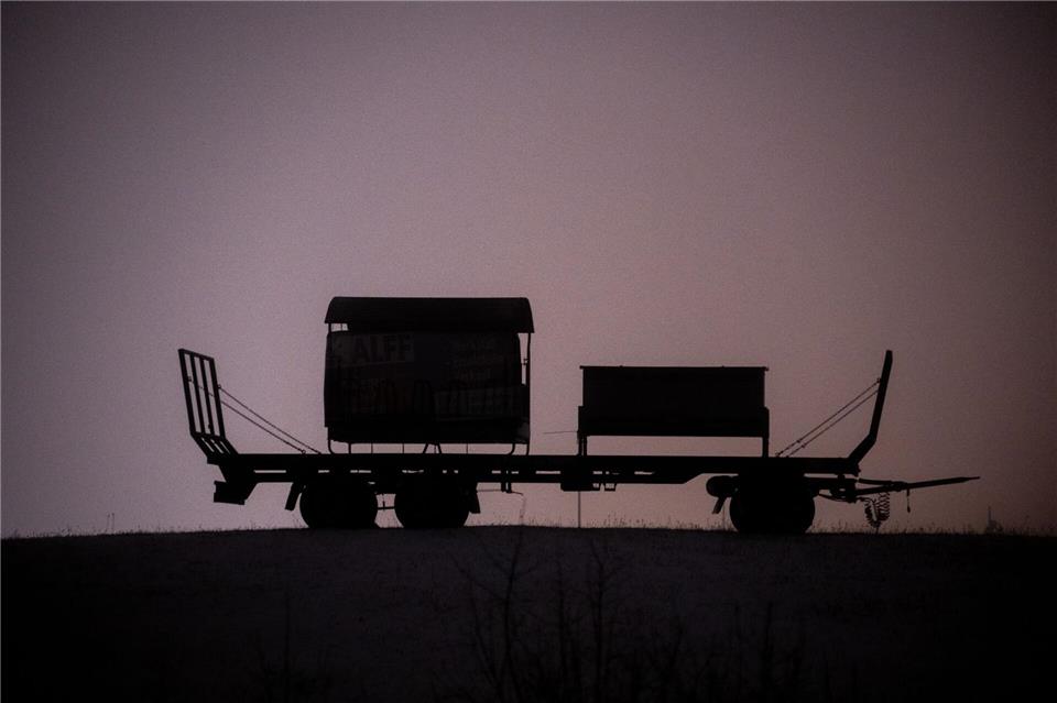 Ein Anhänger steht auf einer schneebedeckten Wiese bei Bitburg und wird von Straßenleuchten erhellt.Harald Tittel/dpa
