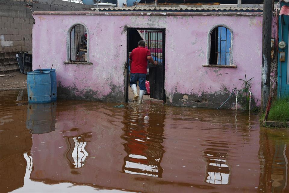 Ein Anwohner betritt sein Haus, das nach dem Durchzug vom Hurrikan „Polo“ in Puerto San Carlos in Mexiko im Wasser steht.Eduardo Verdugo/AP/dpa